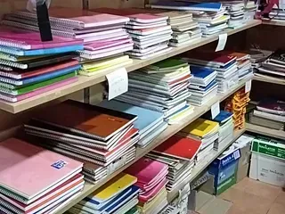 Estantes repletos de diversos cuadernos en una tienda, que muestran pilas de útiles escolares coloridos.