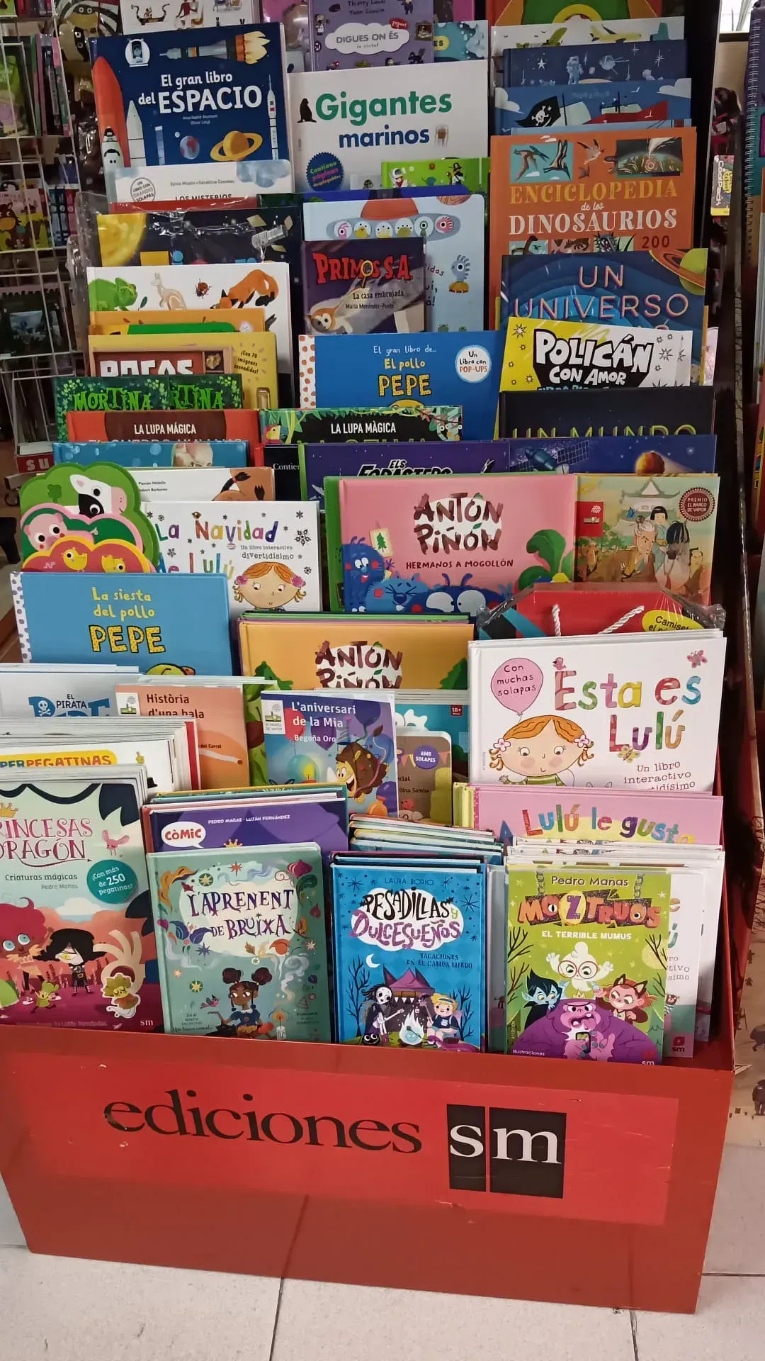 Exhibición de libros infantiles en un expositor de cartón rojo. Los libros tienen portadas coloridas y títulos en español, con la inscripción 