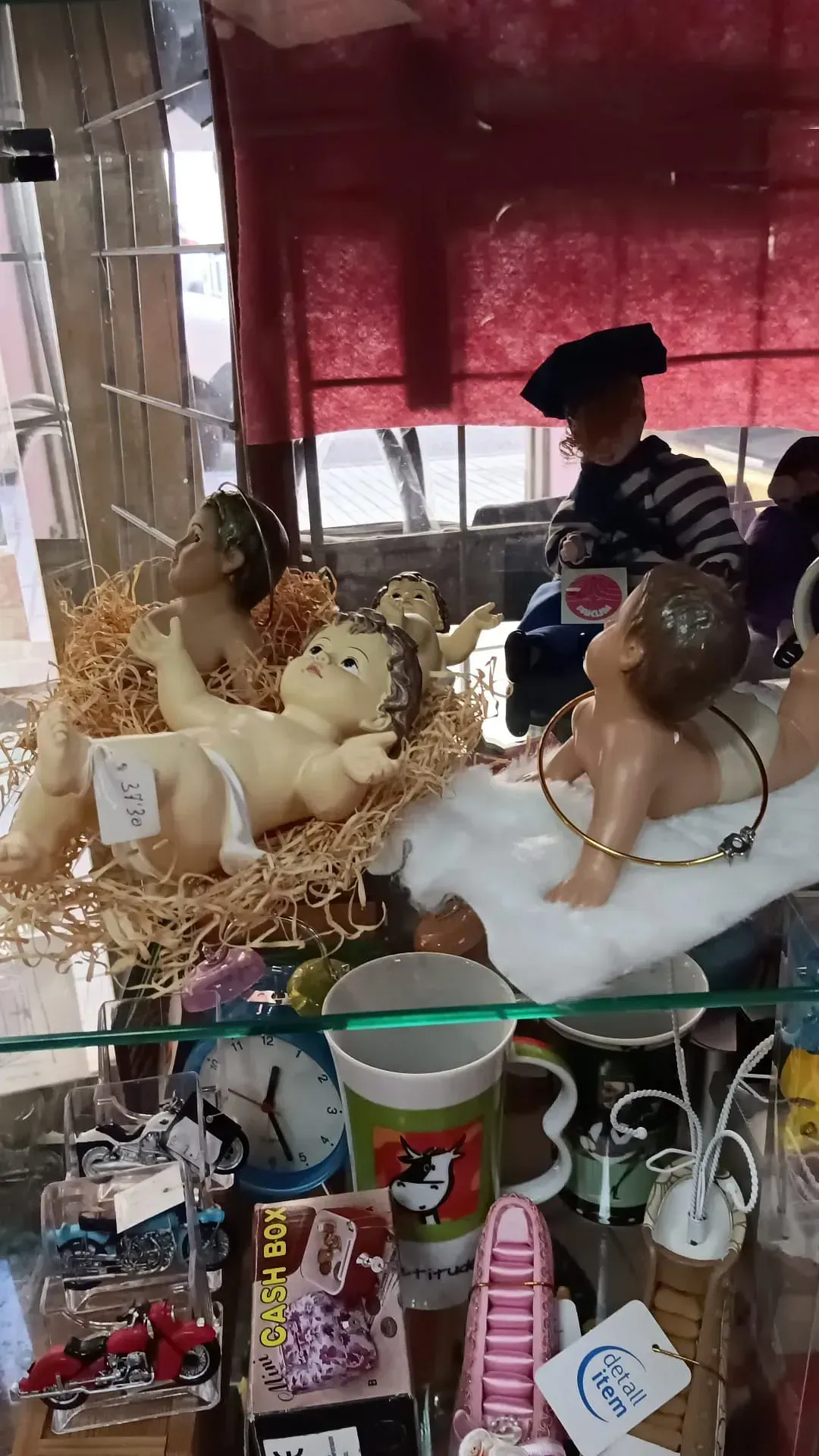 Una vitrina con decoraciones en forma de figuras de bebés, incluido un belén, junto con otras baratijas y tazas.