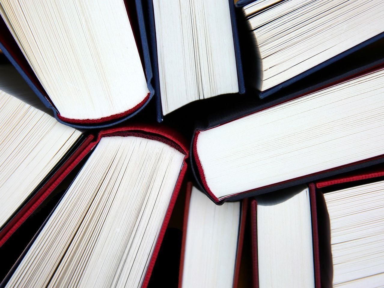 Libros dispuestos en círculo, mostrando las páginas blancas y las cubiertas rojas y azules.