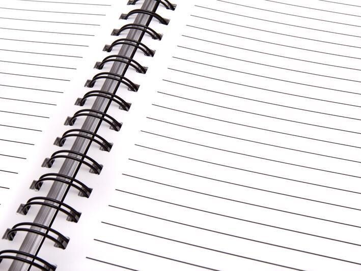 Cuaderno espiral abierto con papel blanco rayado.