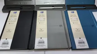 Tres cuadernos con bolígrafos en estuches del mismo color: negro, gris y azul. Los cuadernos están abiertos.