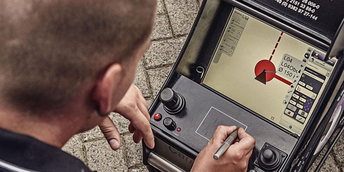 Ein Mann arbeitet an einem Gerät mit einem Stift | ROHREXPERTEN IQ GmbH & Co. KG