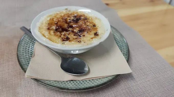 Un cuenco de comida con una cuchara en un plato sobre una mesa.