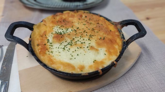 Una cazuela está colocada sobre una tabla de cortar de madera sobre una mesa.
