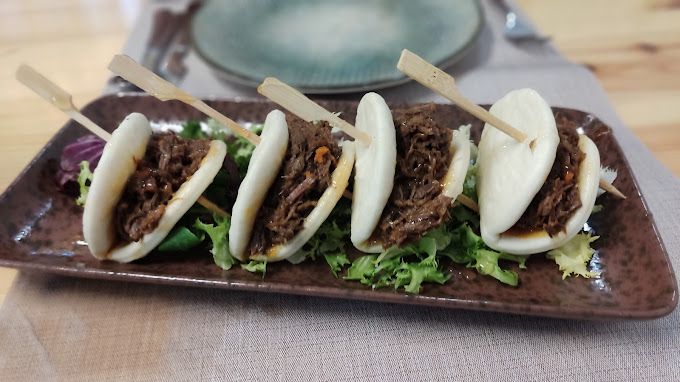 Un plato de comida con carne y verduras en palitos sobre una mesa.