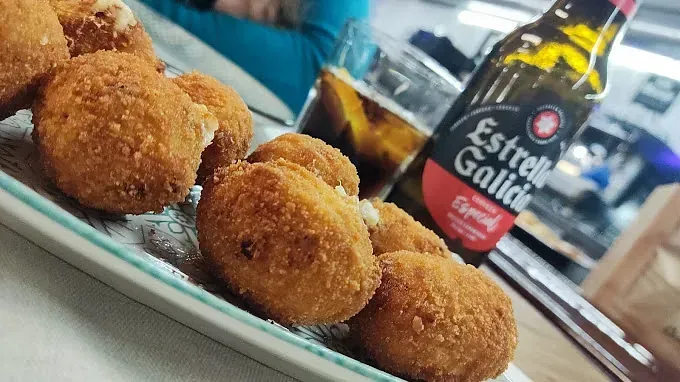 Un plato de comida junto a una botella de cerveza Estrella Galicia