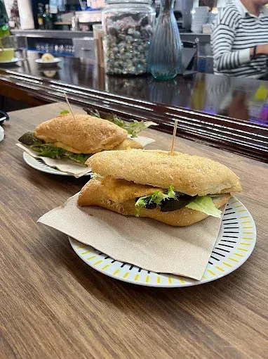 Dos sándwiches están sentados en platos sobre una mesa de madera.