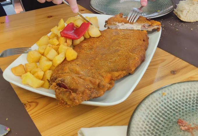 Un plato de comida con carne y patatas en una mesa de madera.