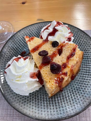 Una rebanada de pastel con crema batida y salsa en un plato.