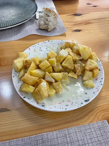 Un plato de comida está sobre una mesa de madera al lado de un trozo de pan.