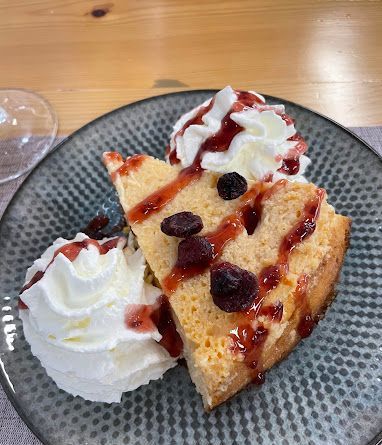 Una rebanada de pastel con crema batida y bayas en un plato.