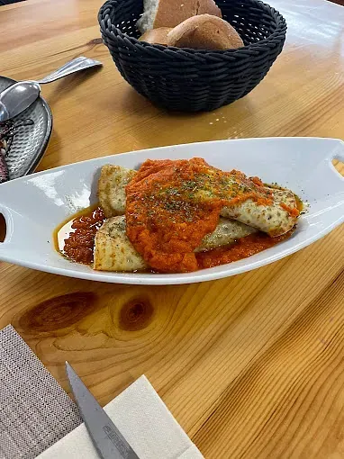 Un plato de comida está sobre una mesa de madera al lado de una cesta de pan.