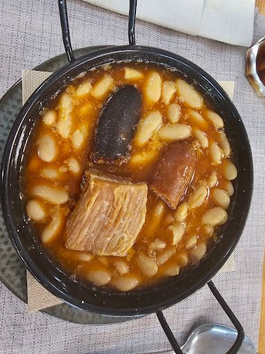 Un tazón de sopa con carne y frijoles en una mesa.