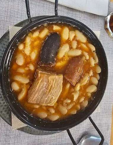 Un tazón de sopa con carne y frijoles en una mesa.