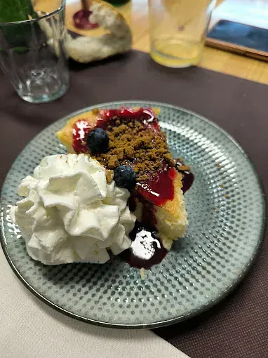 Una rebanada de tarta de queso con crema batida en un plato.