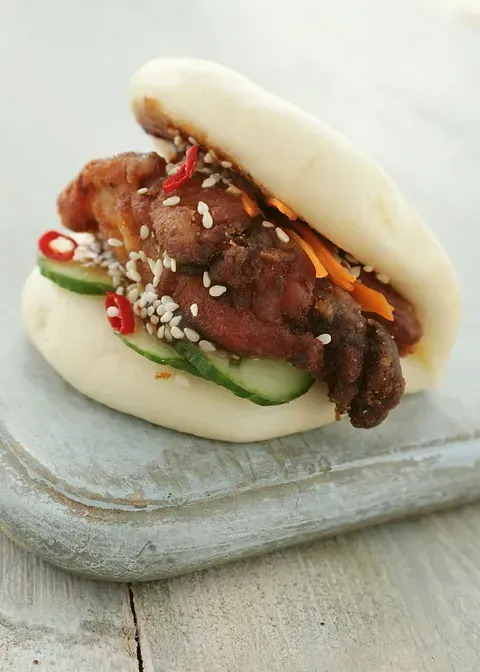 Un primer plano de un sándwich con carne y verduras en una tabla de cortar.