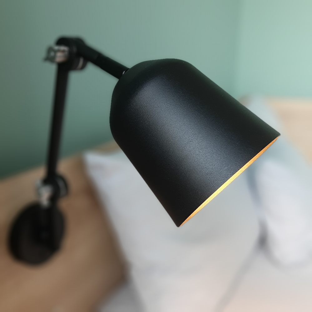 Eine schwarze Lampe steht auf einem Bett mit weißen Kissen