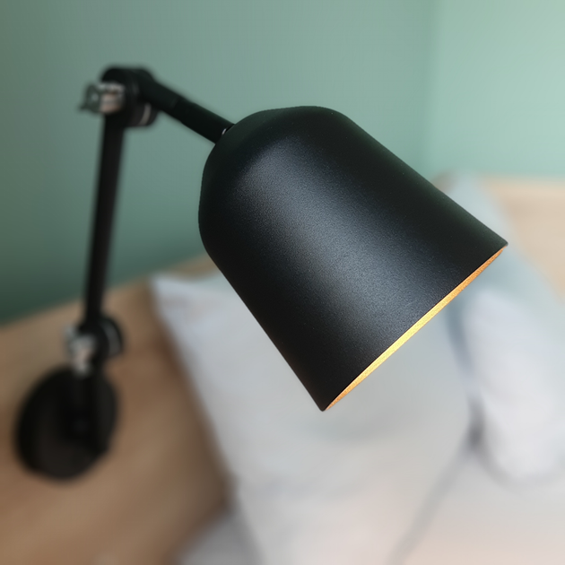 Corporate Rate anfragen Schwarze Leselampe mit verstellbarem Arm, der zum Betrachter hin ausgerichtet ist. Das Innere der Lampe ist beleuchtet.