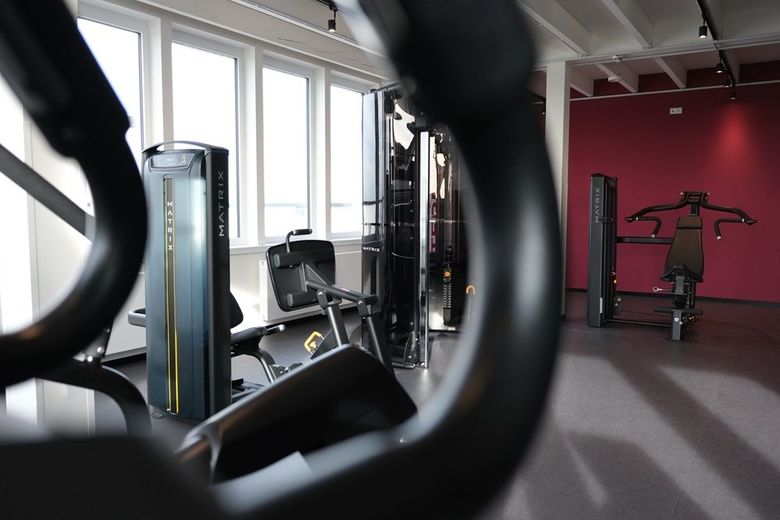 Ein Fitnessstudio mit vielen Geräten und einer roten Wand