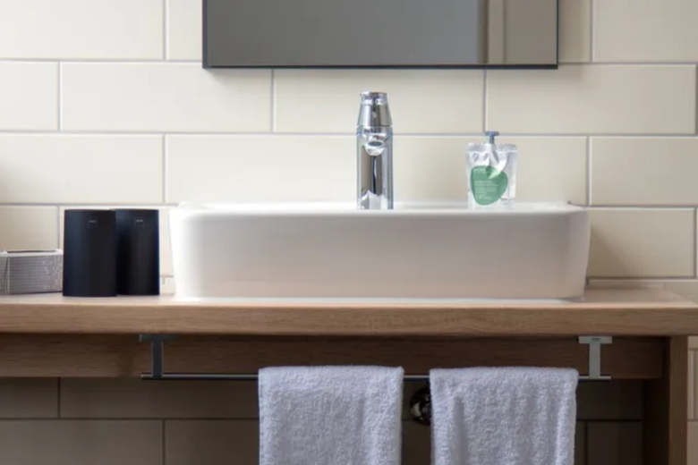 Apartmenthotel sylc. | Badezimmer | Waschbecken mit Handtüchern Ein Waschbecken im Badezimmer mit zwei Handtüchern darunter hängen in einem Hotelzimmer