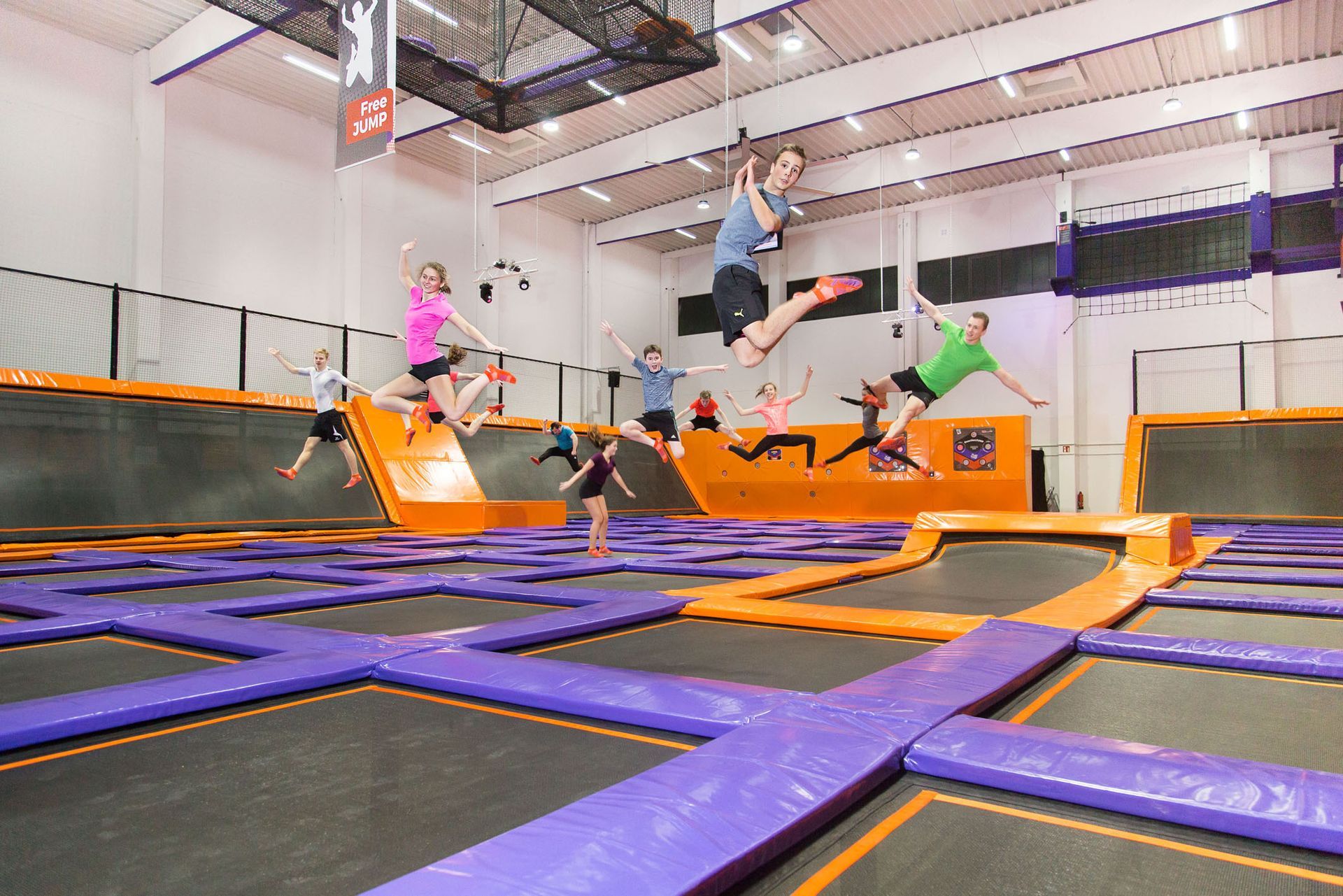 Eine Gruppe von Menschen springt in einer Turnhalle auf Trampolinen.