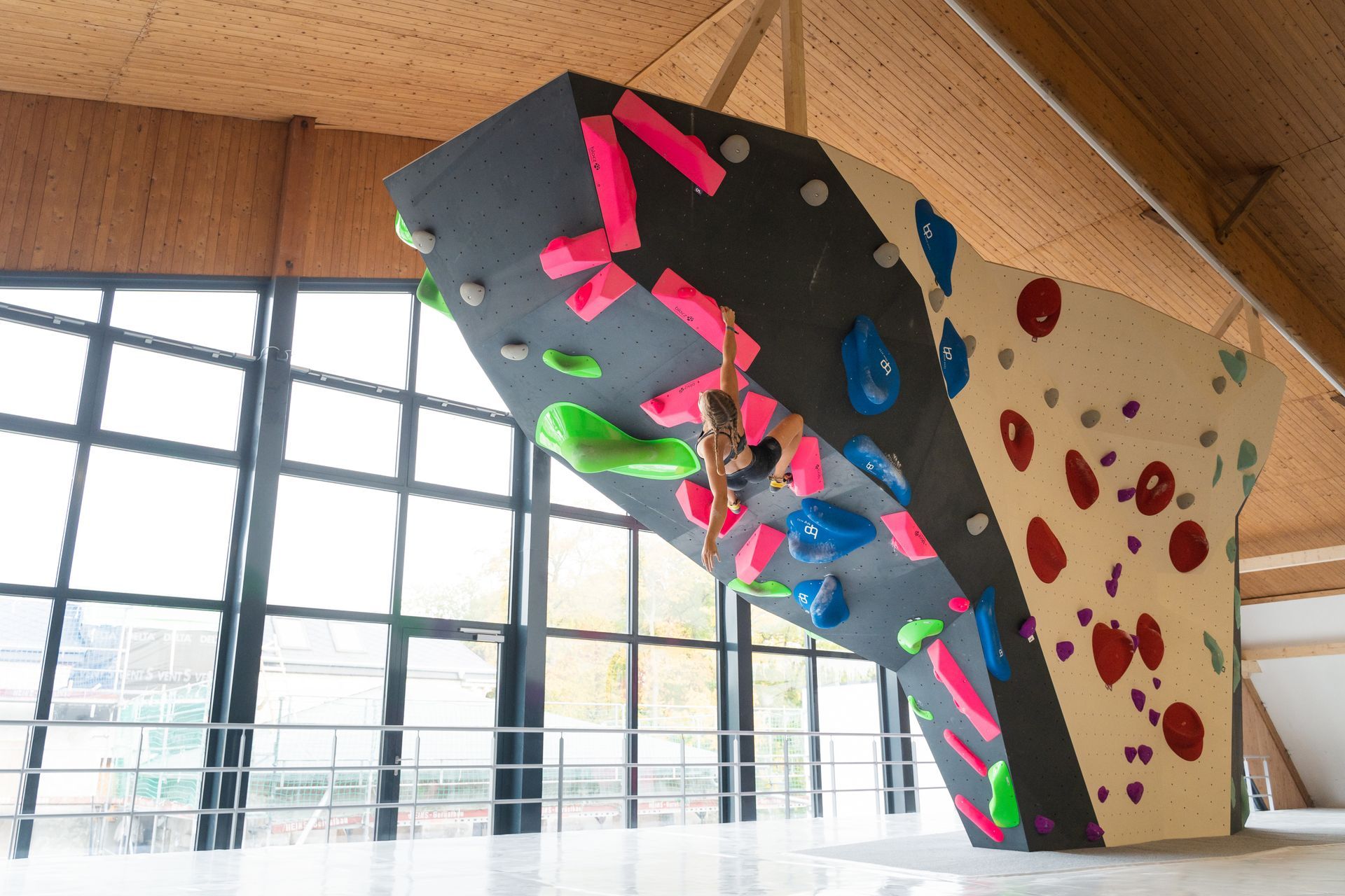 Eine Person klettert in einer Turnhalle eine Kletterwand hinauf.