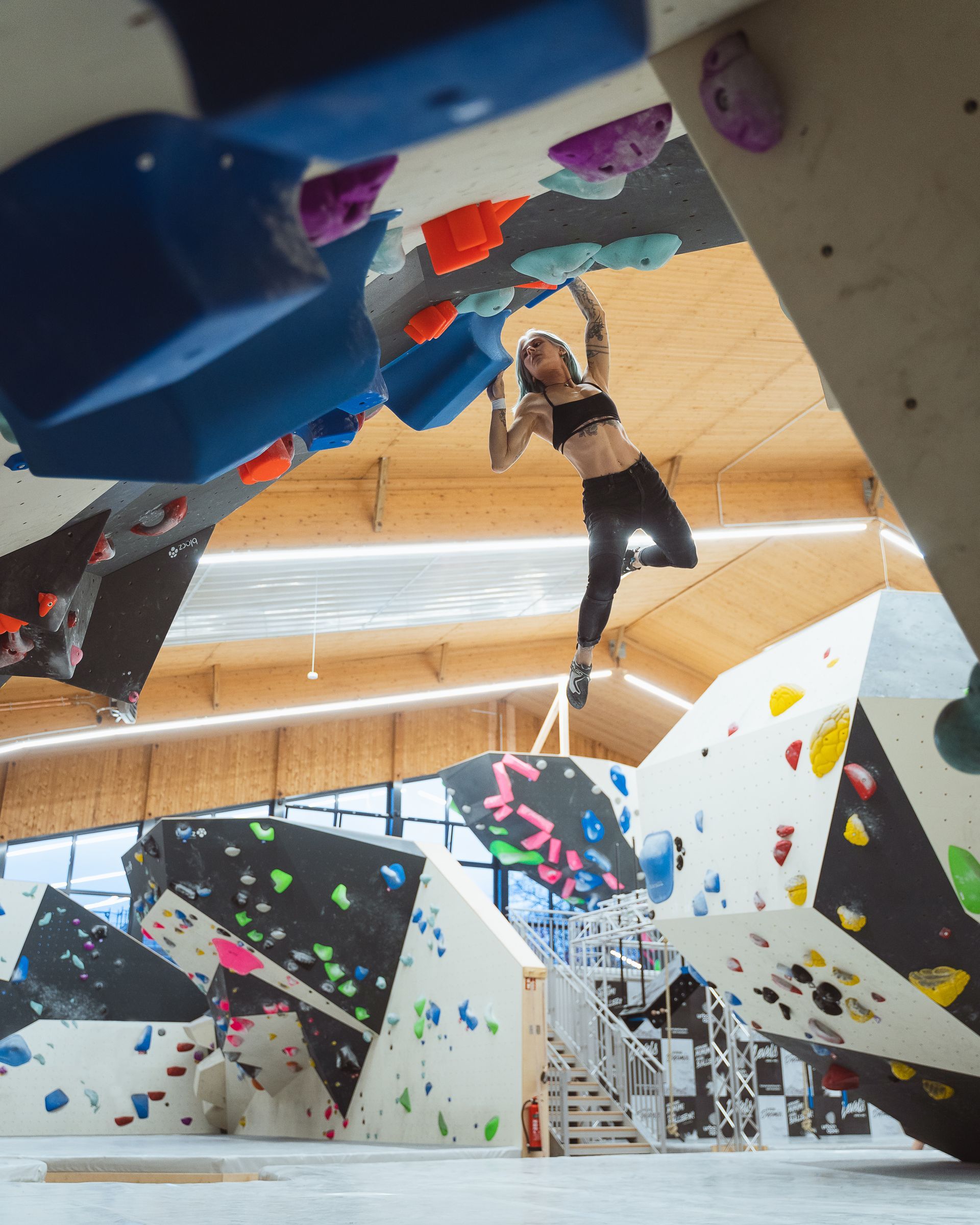 Eine Frau klettert in einer Turnhalle eine Kletterwand hinauf.