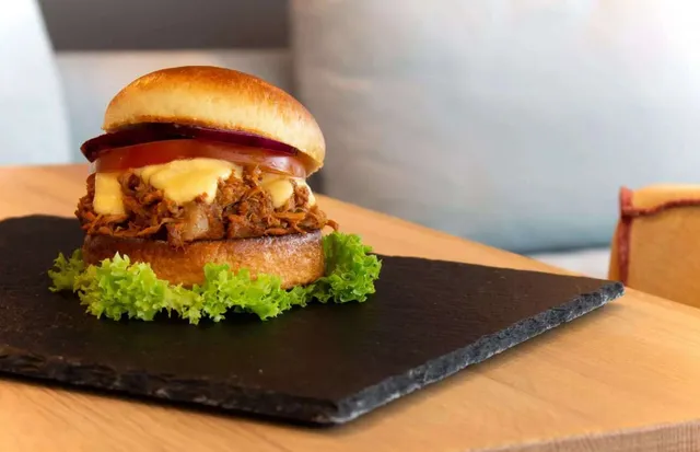 Ein Hamburger liegt auf einem schwarzen Teller auf einem Tisch.