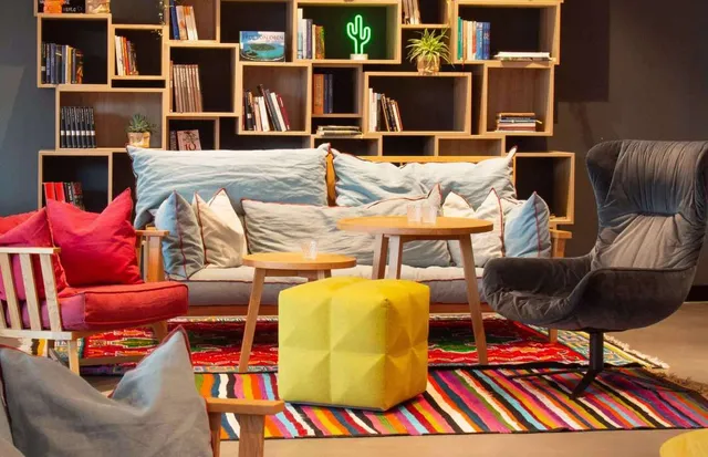 Ein Aufenthaltszimmer mit einer Couch, Stühlen, Ottomanen und einem Bücherregal