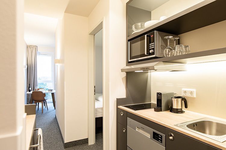 Eine Küche in einem Hotelzimmer mit Spüle, Mikrowelle und Geschirrspüler.