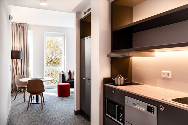 Ein modernes Apartment mit einer Küche und Sitzbereich mit Tisch und Stühlen. Die Küche verfügt über Mikrowelle und Spüle.