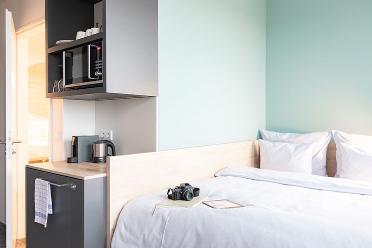 Ein Schlafzimmer mit einem Bett, eine Küche und eine Mikrowelle.