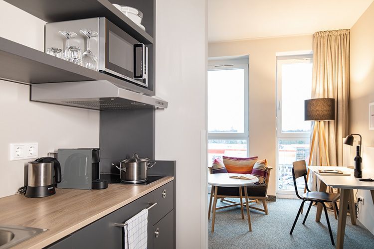 Eine Küche in einem Hotelzimmer mit Mikrowelle, Spüle, Tisch und Stühlen.