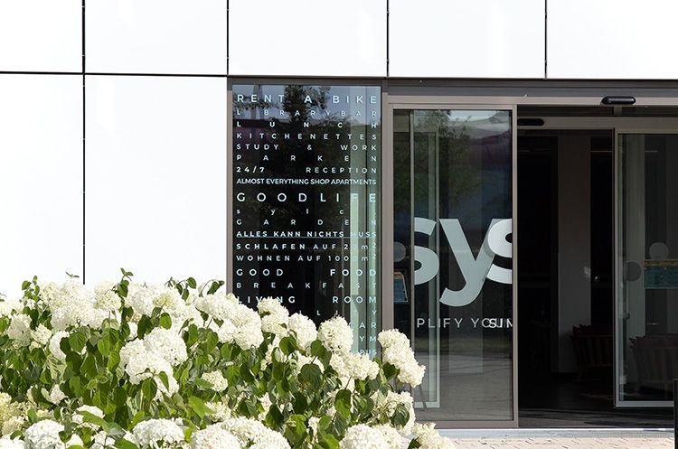 sylc. Apartmenthotel | EATERY | Salatbuffet Buffetbereich mit Holzarbeitsplatten, verschiedenen Speisen, schwarzen Pendelleuchten und Akzenten aus Edelstahl.