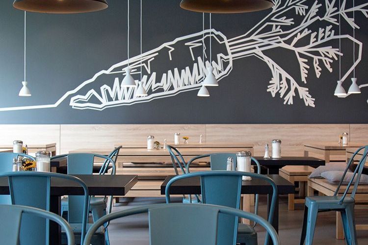 sylc. Apartmenthotel | EATERY | Essbereich Ein Restaurant mit Tischen und Stühlen und einem Wandgemälde an der Wand