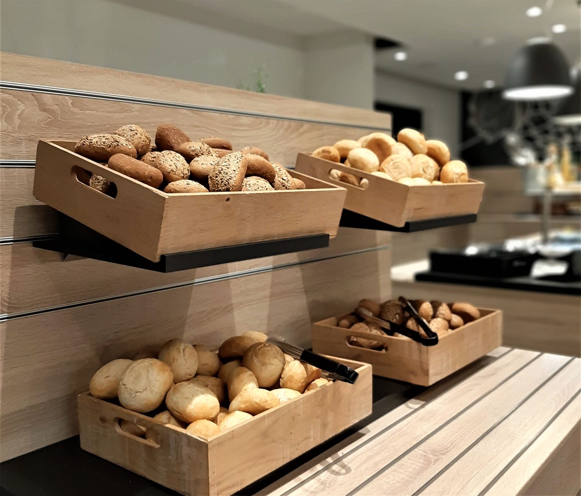 Holzkisten mit verschiedenen Brötchensorten auf einer Etagenvitrine in einem Restaurantbuffet.