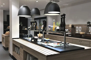 sylc. Apartmenthotel | EATERY | Salatbuffet Ein Buffet in einem Restaurant mit schwarzen Lampen, die von der Decke hängen.