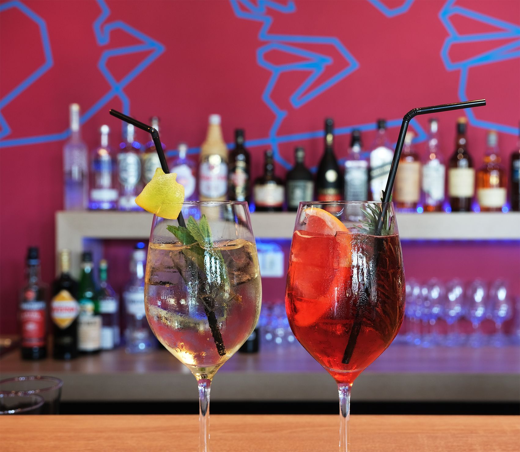 Zwei Getränke stehen auf einer Bar mit Flaschen im Hintergrund