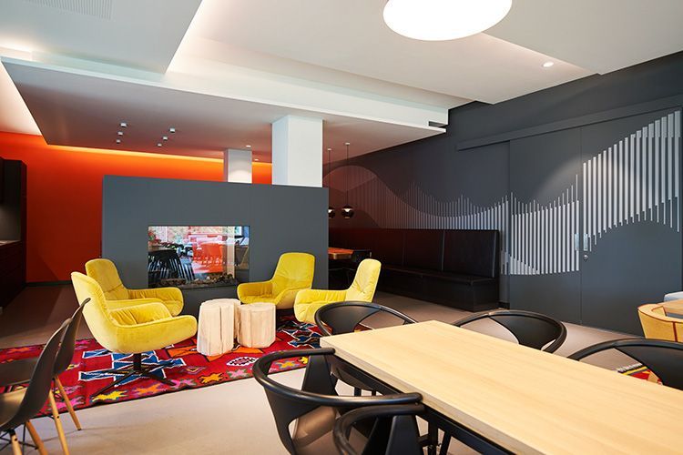Living Room mit gelben Sesseln, farbenfrohem Teppich, Fernseher und Holztischen in einem eleganten, dunklen Interieur