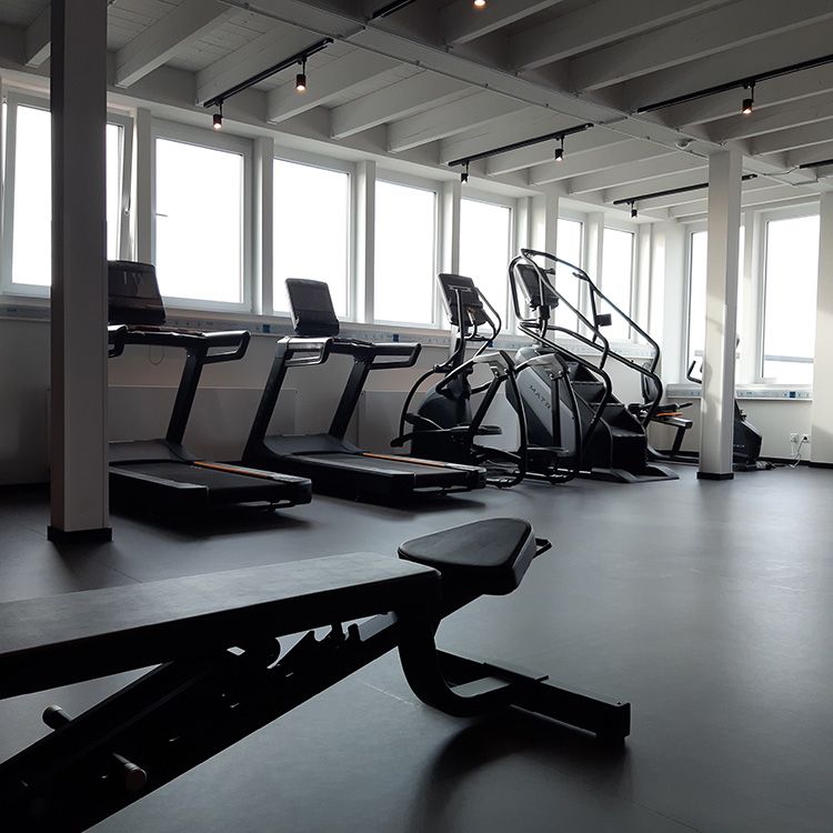 Ein Fitnessstudio mit Laufbändern, Treppen und einer Bank