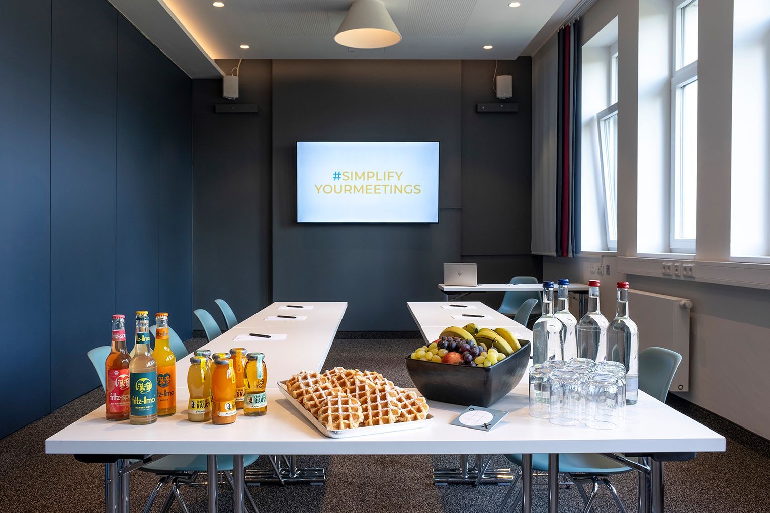 Study III Meetingraum mit einem gedeckten Tisch mit Getränken, Gebäck, Obst und Wassergläsern