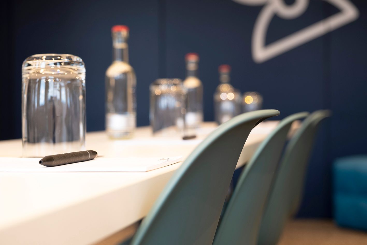 Konferenztisch mit Wasserflaschen, Gläsern und Stühlen im Vordergrund