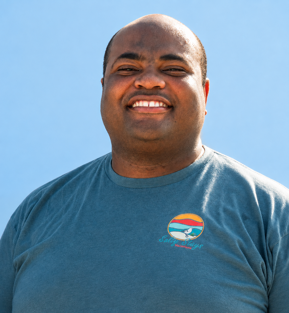 Smiling person in a teal T-shirt against a blue sky background