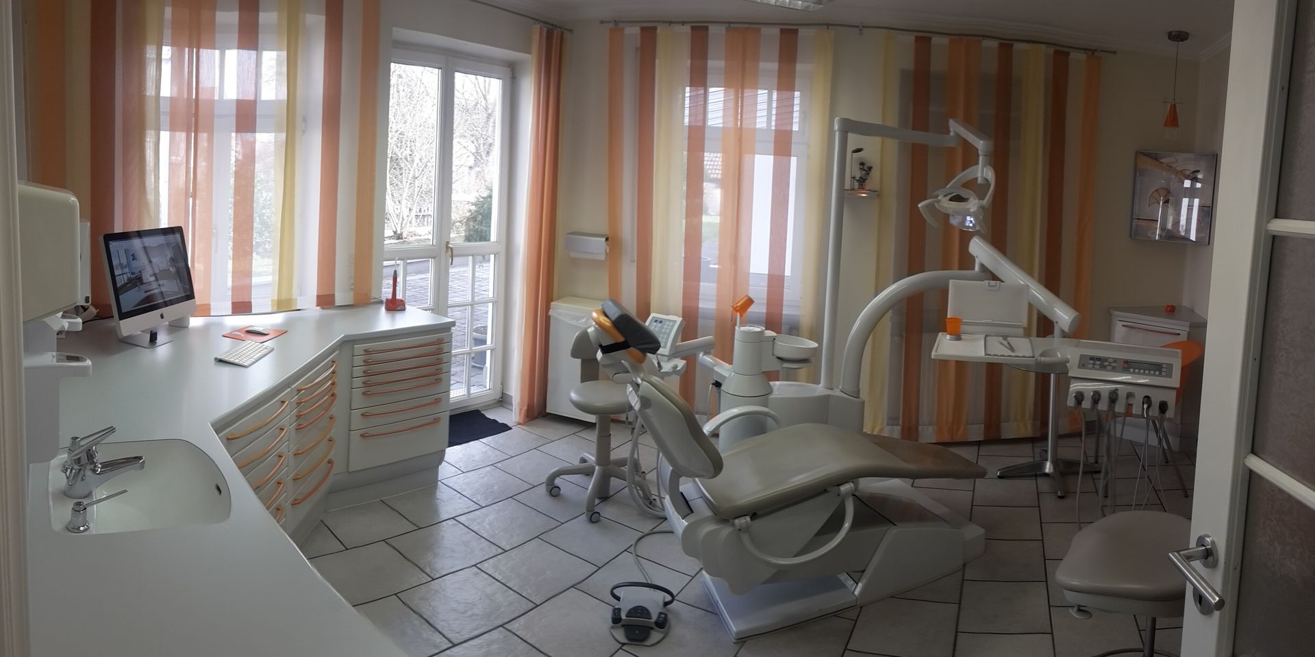 Behandlungsraum mit einem Zahnarztstuhl und einem Schreibtisch