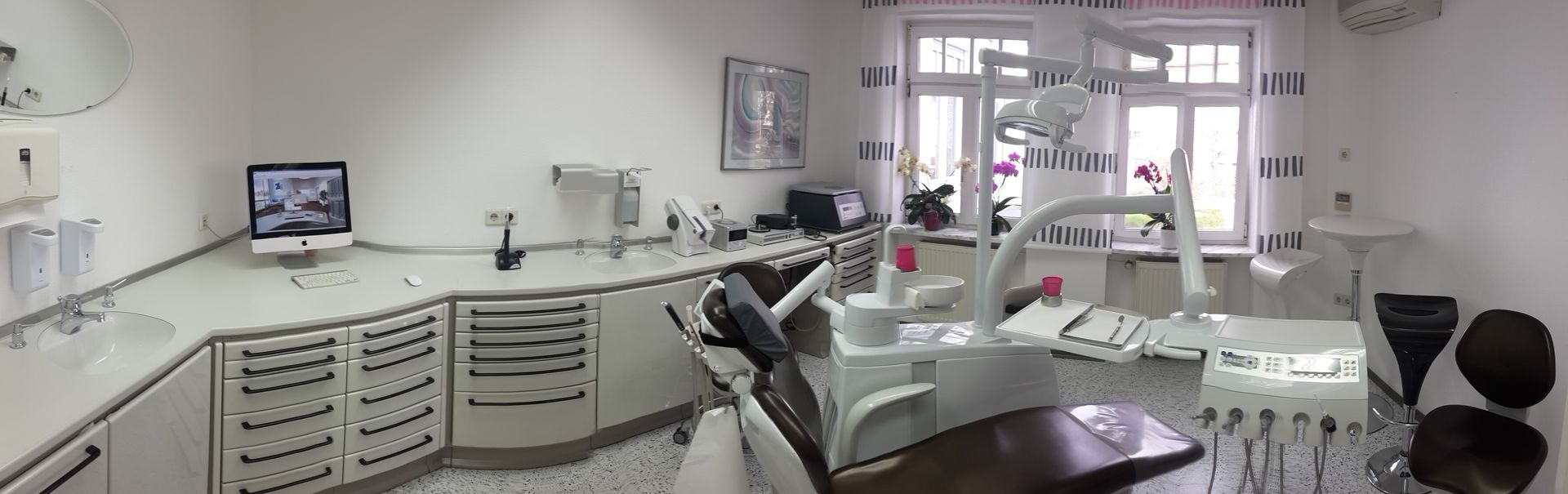Behandlungsraum mit einem Zahnarztstuhl und einem Computer auf der Theke
