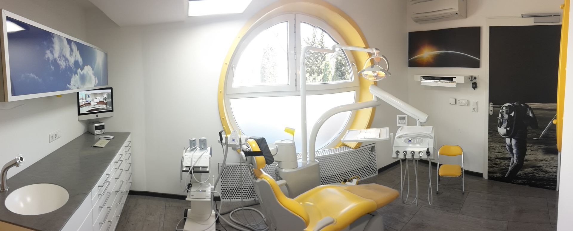 Behandlungsraum mit einem gelben Zahnarztstuhl und einem Waschbecken