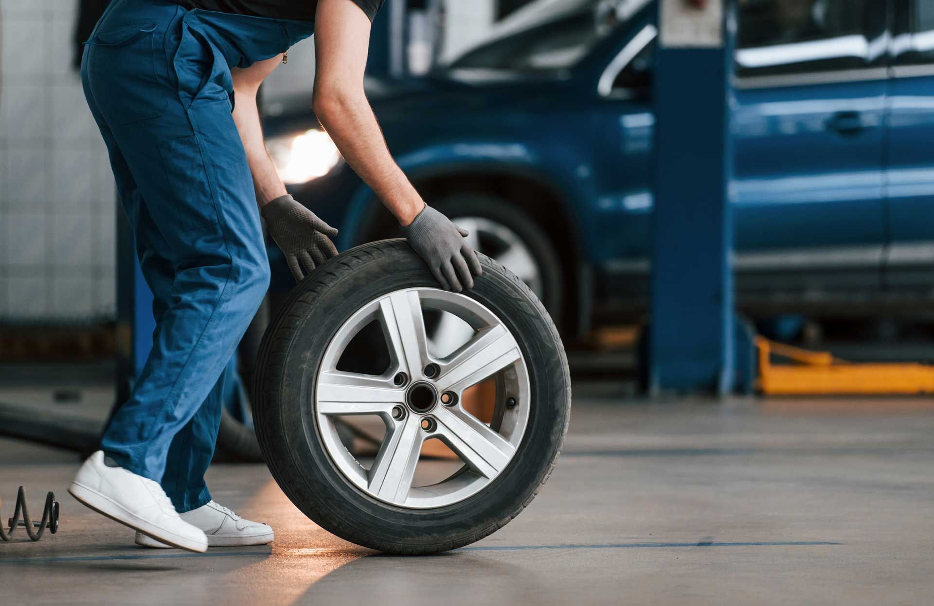Un garagiste faisant rouler un pneu dans un garage automobile
