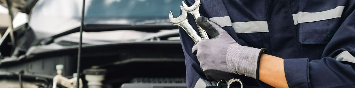 Silhouette de mécanicien tenant des outils devant une voiture avec le capot ouvert