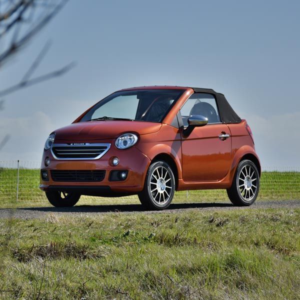 Voiture orange devant un champ